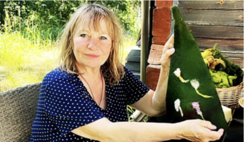 Woman holding handmade sauna hat at workshop in Finland