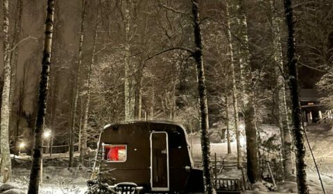 Vuokrattava kärrysauna metsäympäristössä iltavalaistuksessa.