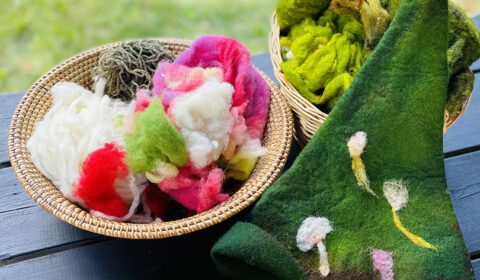 Huovutettu villainen saunahattu ja työpajassa käytettäviä villamateriaaleja.